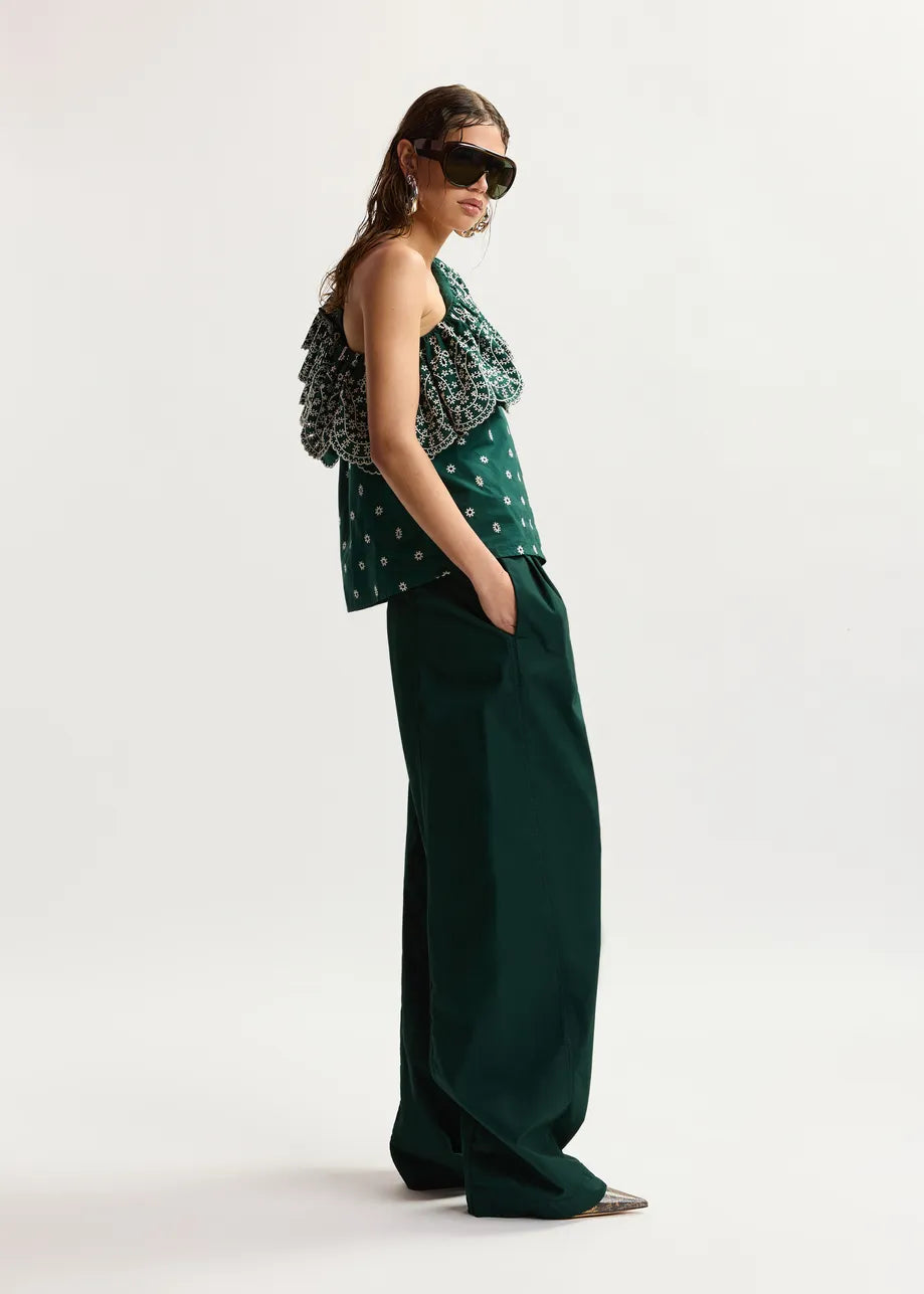 Woman wearing a green patterned top and dark green wide-leg pants on a white background