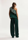 Woman wearing a green one-shoulder top and wide-leg pants on a white background