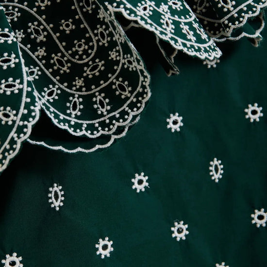 Close-up of green fabric with white embroidery patterns