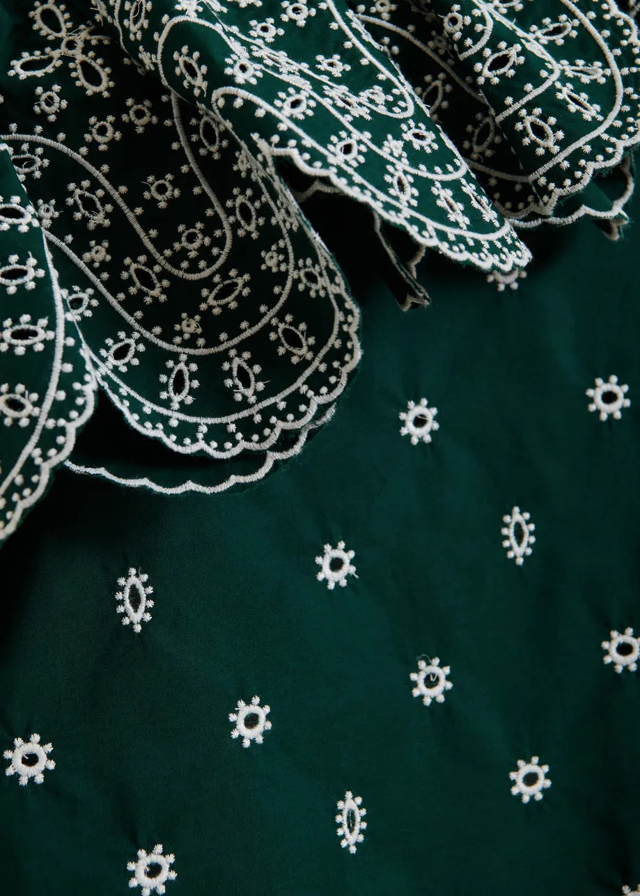 Close-up of green fabric with white embroidery patterns