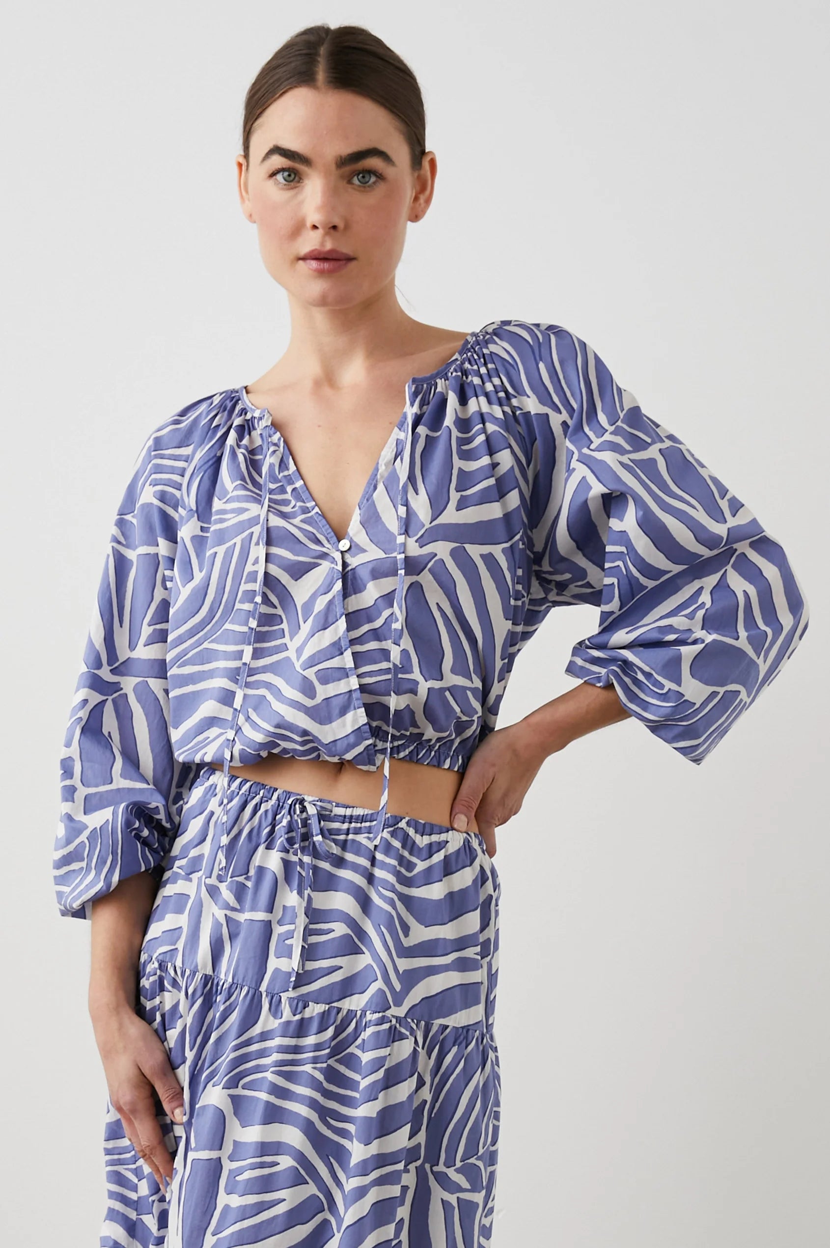 Cropped cross over top with notch neck and long full sleeves with elasticated sleeves in white and blue geometric pattern