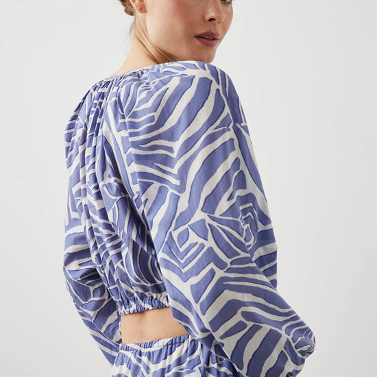 Cropped cross over top with notch neck and long full sleeves with elasticated sleeves in white and blue geometric pattern