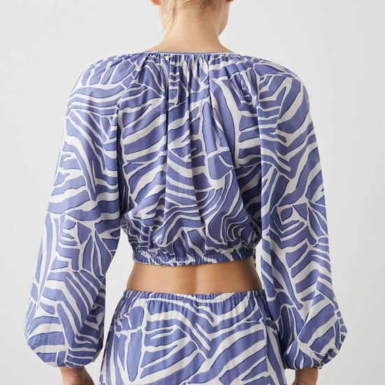 Cropped cross over top with notch neck and long full sleeves with elasticated sleeves in white and blue geometric pattern