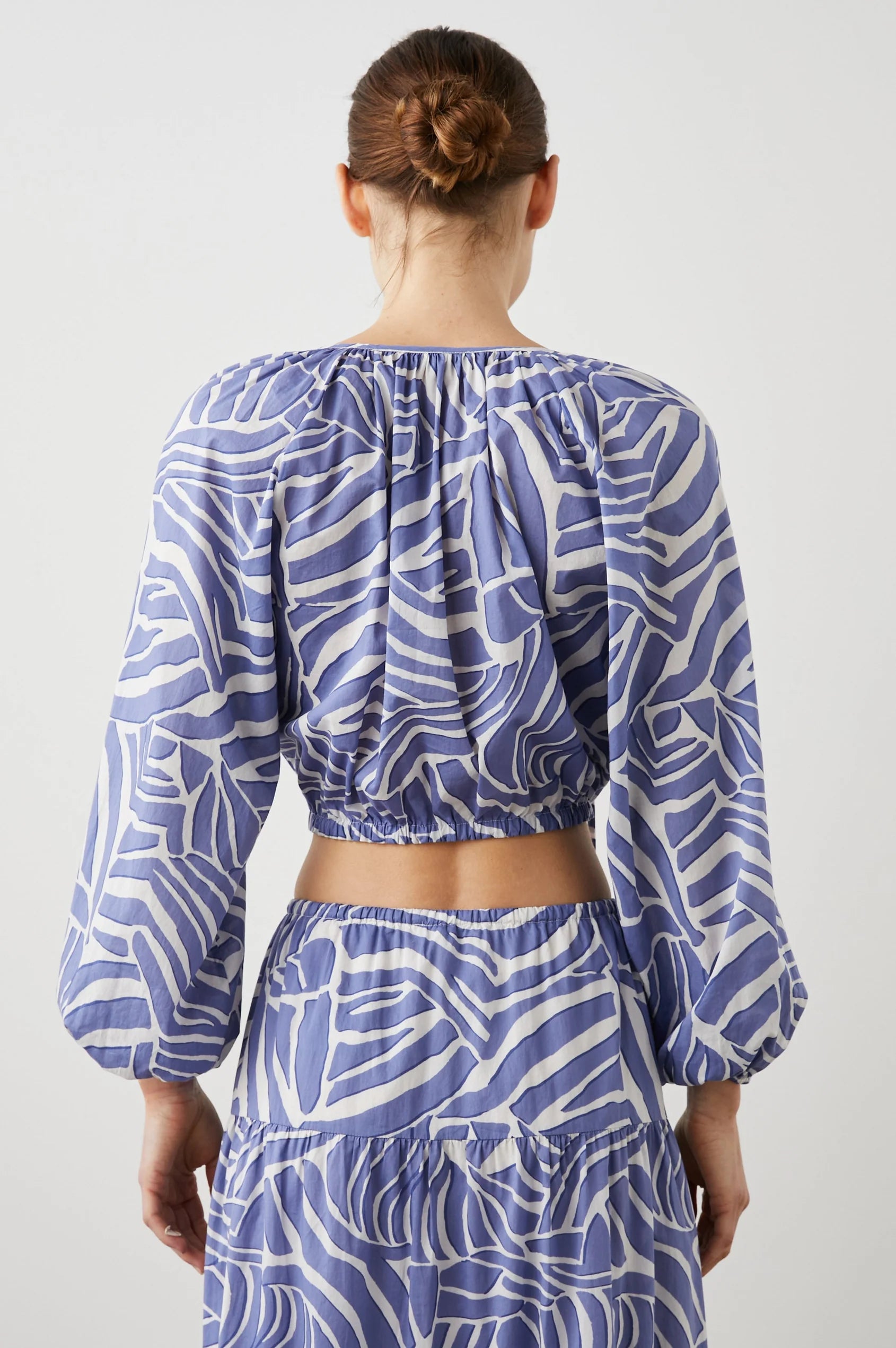 Cropped cross over top with notch neck and long full sleeves with elasticated sleeves in white and blue geometric pattern