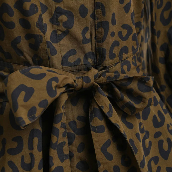 Close-up of a leopard-print fabric garment with a tied waist belt, showing a brown base with dark navy spots.