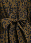 Close-up of a leopard-print fabric garment with a tied waist belt, showing a brown base with dark navy spots.