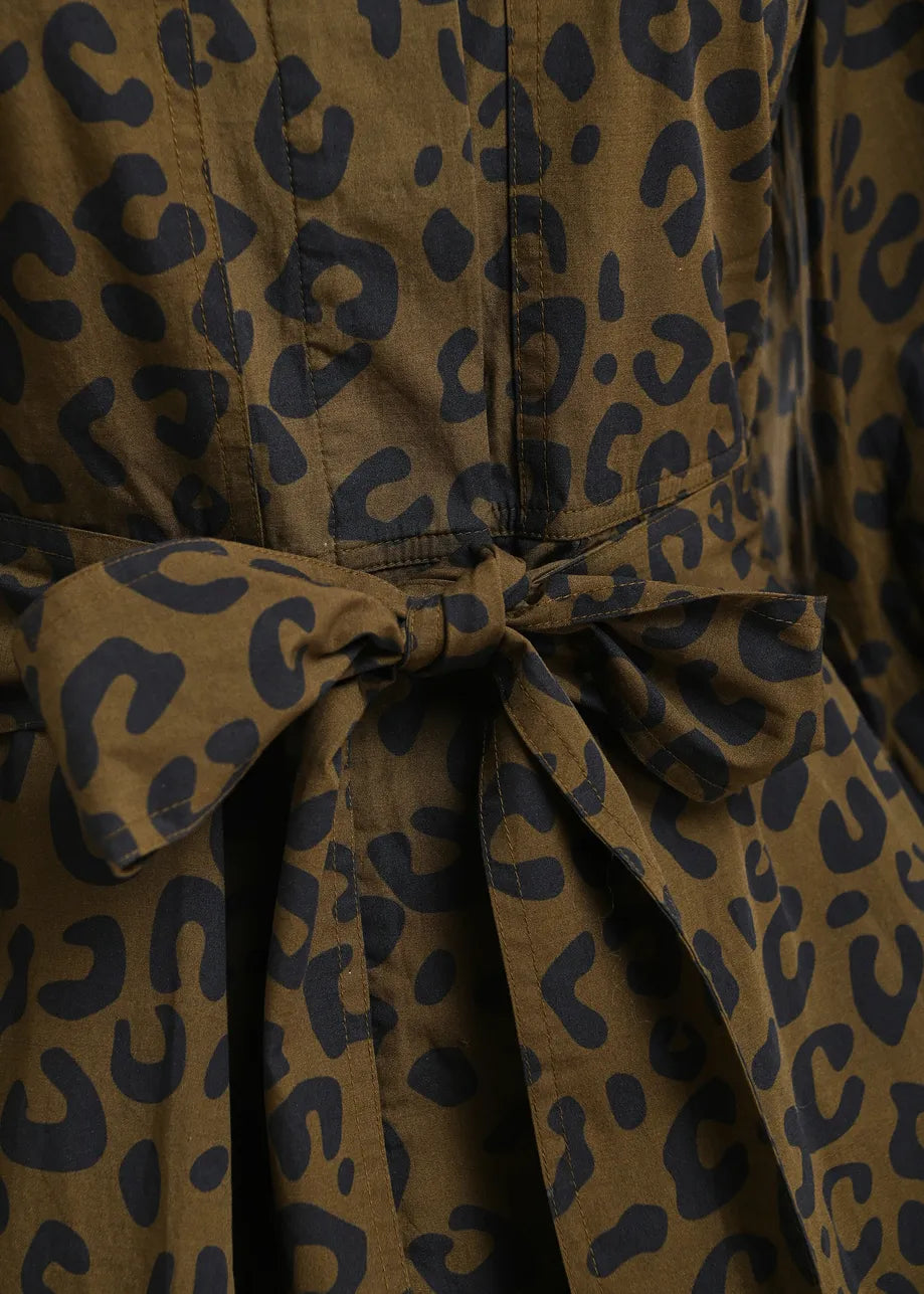 Close-up of a leopard-print fabric garment with a tied waist belt, showing a brown base with dark navy spots.