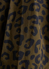 Close-up of a leopard print fabric with dark navy blue spots on a warm brown background.
