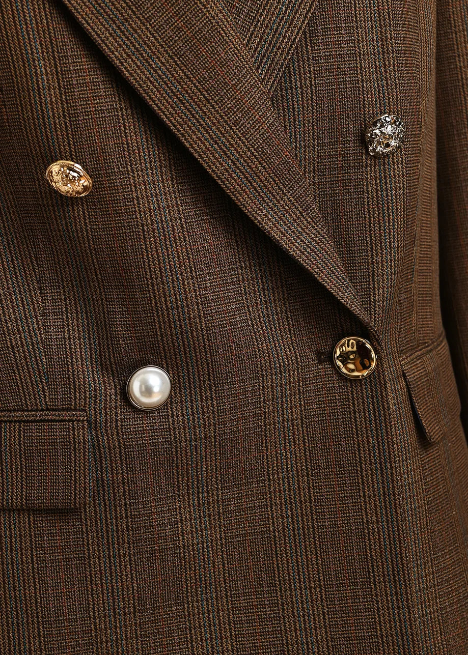 Close-up of a brown plaid double-breasted blazer with decorative buttons, including a pearl button and textured gold and silver buttons.
