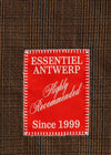 A close-up of a brown and black plaid fabric with a prominent red rectangular patch reading 'ESSENTIEL ANTWERP Highly Recommended Since 1999' in white text.