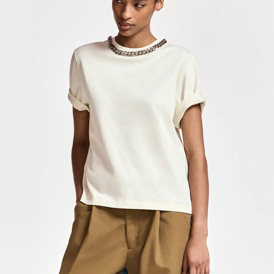 woman wearing White tshirt with a chain and brown trousers on  a white background