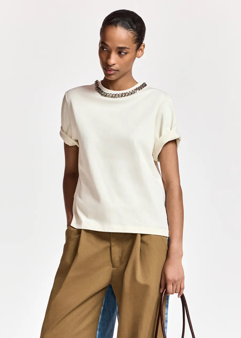 woman wearing White tshirt with a chain and brown trousers on  a white background