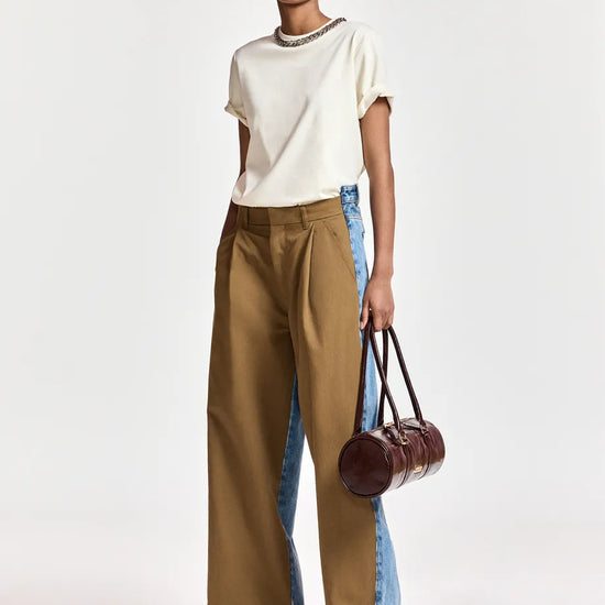 woman wearing White tshirt with a chain and brown trousers on  a white background