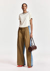 woman wearing White tshirt with a chain and brown trousers on  a white background