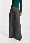 A model wearing high-waisted, wide-leg gray plaid trousers with a dark brown belt, paired with a dark green long-sleeve top and brown pointed-toe heels, against a plain white studio background.