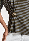 Close-up of a person wearing a horizontally striped knit top in olive green and heather gray, gathered at the waist with a metallic heart-shaped ring.