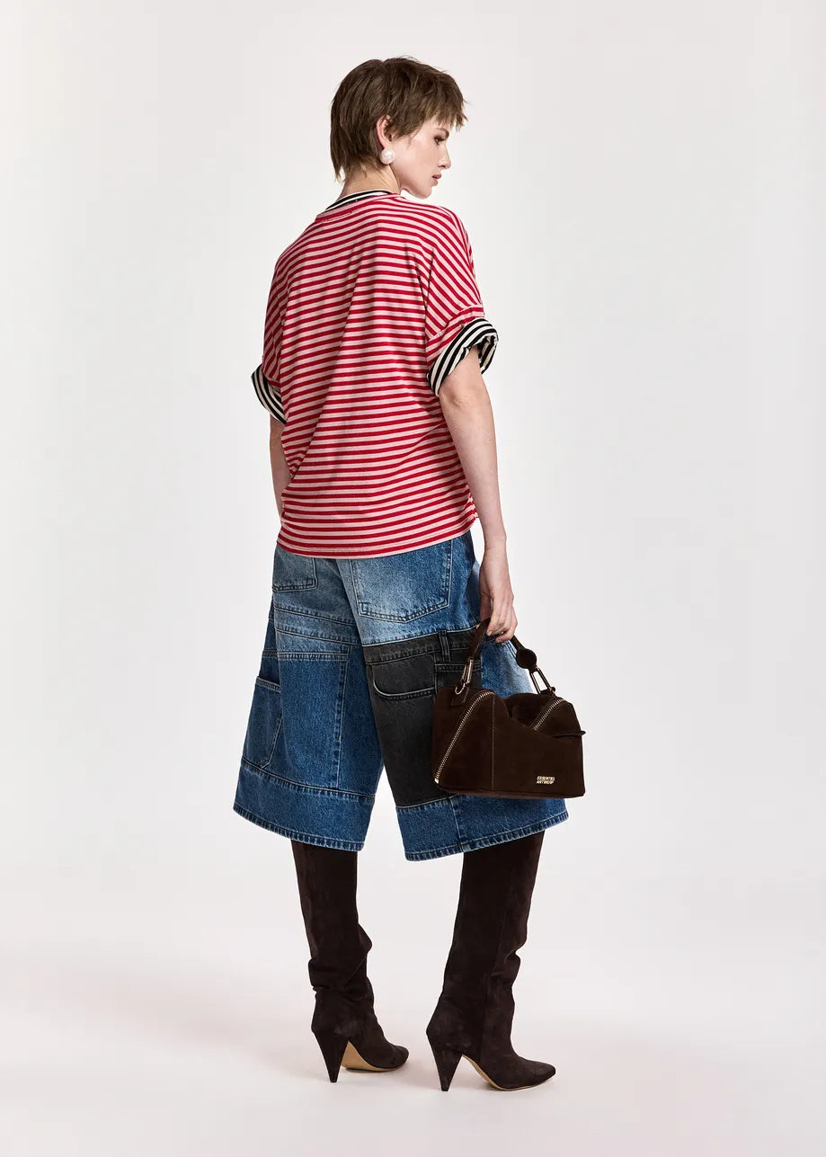 A model shown from the back wearing a red and white striped short-sleeve top, a denim patchwork skirt, black over-the-knee boots, and holding a brown handbag against a plain white studio background.