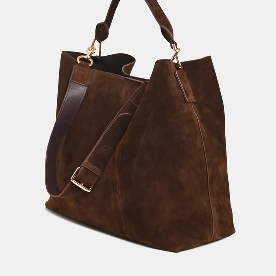 A dark brown suede tote bag with a matching brown leather shoulder strap and gold-tone hardware, shown on a light gray background.