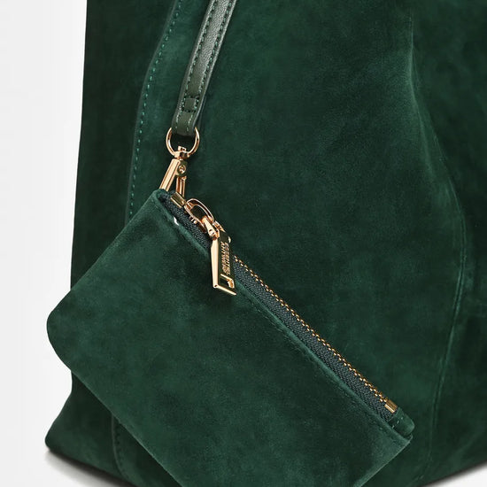 Close-up of a dark green suede tote bag with a matching shoulder strap and a small zippered pouch attached by gold-tone hardware.