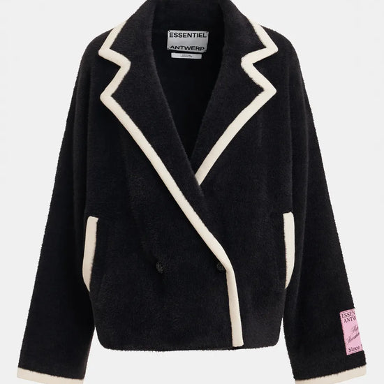 A black sherpa fleece wrap jacket with cream-colored contrast piping and trim, featuring a pointed lapel design, front pockets, and a pink 'ESSENTIALS AUTHENTIC' patch on the left sleeve cuff, shown against a light gray background.