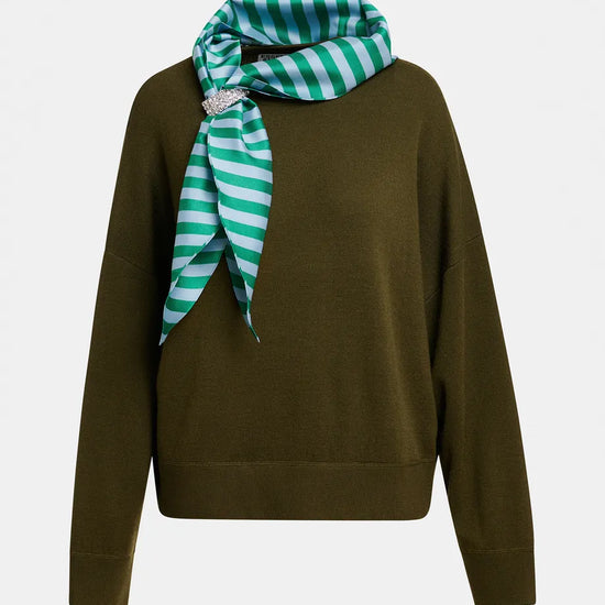An olive green knit sweater with a green and white striped silk scarf tied around the neck, featuring a small silver-tone brooch, shown against a plain light gray background.