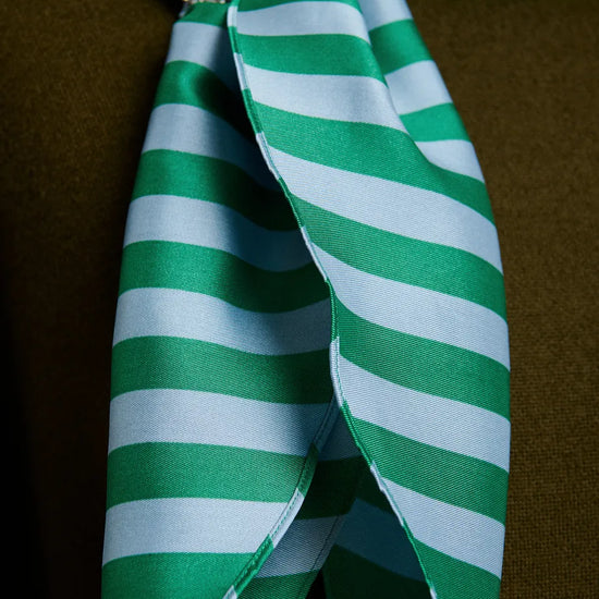 Green and white striped bow with a decorative brooch on a brown background