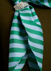 Green and white striped bow with a decorative brooch on a brown background