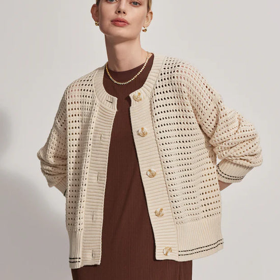 Button through pointelle knit cardigan in ecru with green details layered over a dress