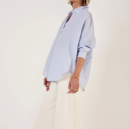Woman wearing Mondo Corsini blue and white Pinstripe blouse on a white background. Side view