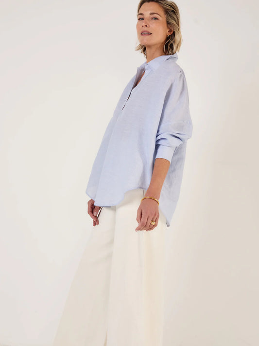 Woman wearing Mondo Corsini blue and white Pinstripe blouse on a white background. Side view