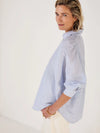Woman wearing Mondo Corsini blue and white Pinstripe blouse on a white background. Other side view