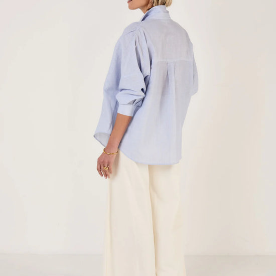 Woman wearing Mondo Corsini blue and white Pinstripe blouse on a white background. Rear View