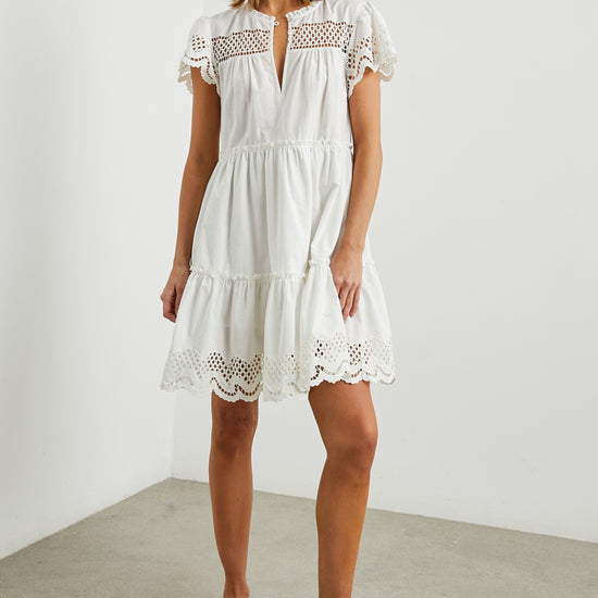 White cotton mini dress with eyelet inserts and scalloped hem and sleeves