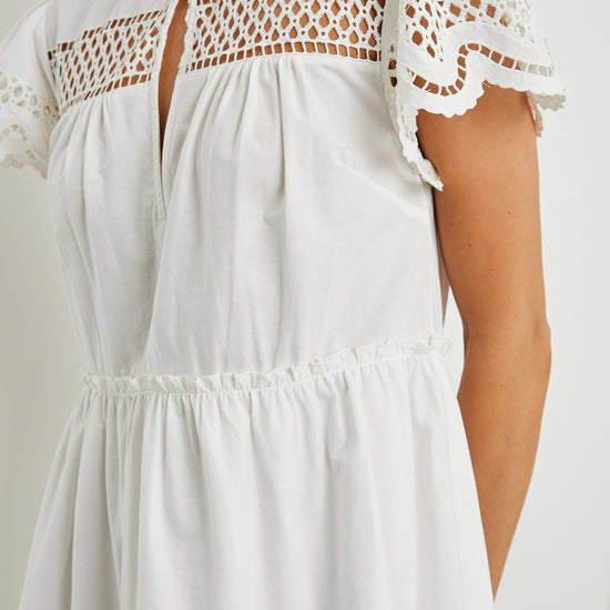 White cotton mini dress with eyelet inserts and scalloped hem and sleeves