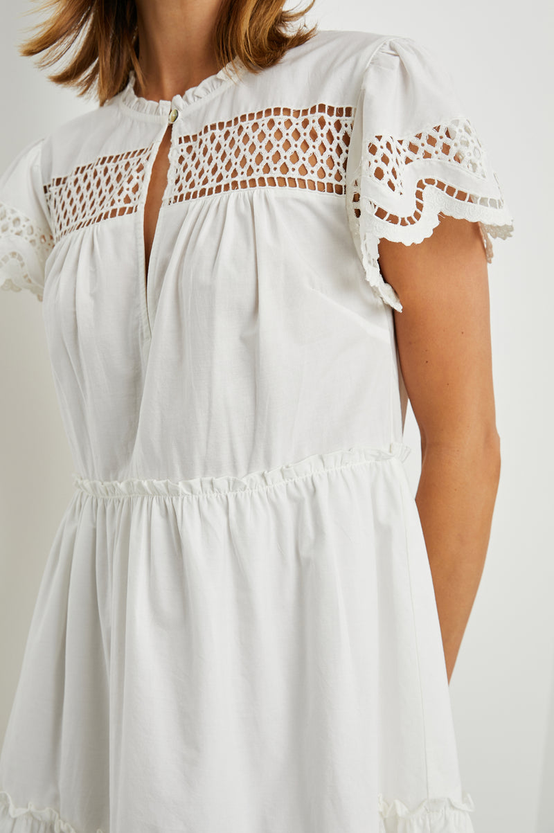 White cotton mini dress with eyelet inserts and scalloped hem and sleeves