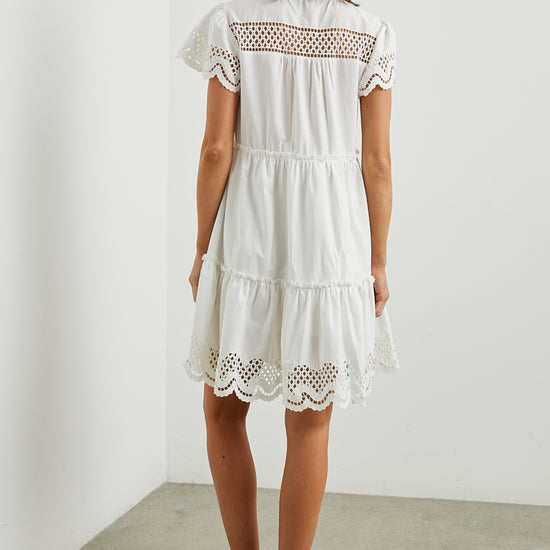 White cotton mini dress with eyelet inserts and scalloped hem and sleeves