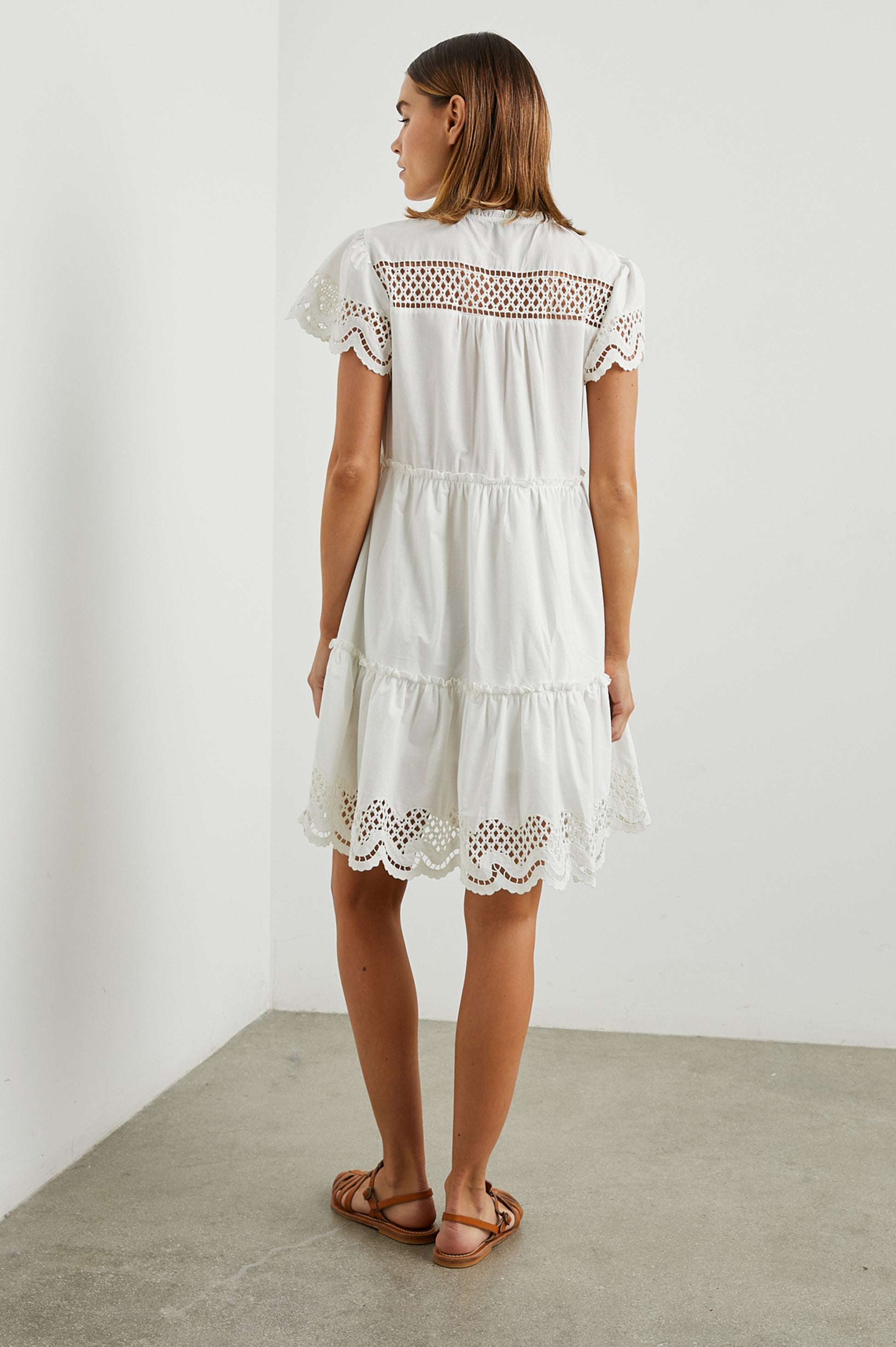 White cotton mini dress with eyelet inserts and scalloped hem and sleeves