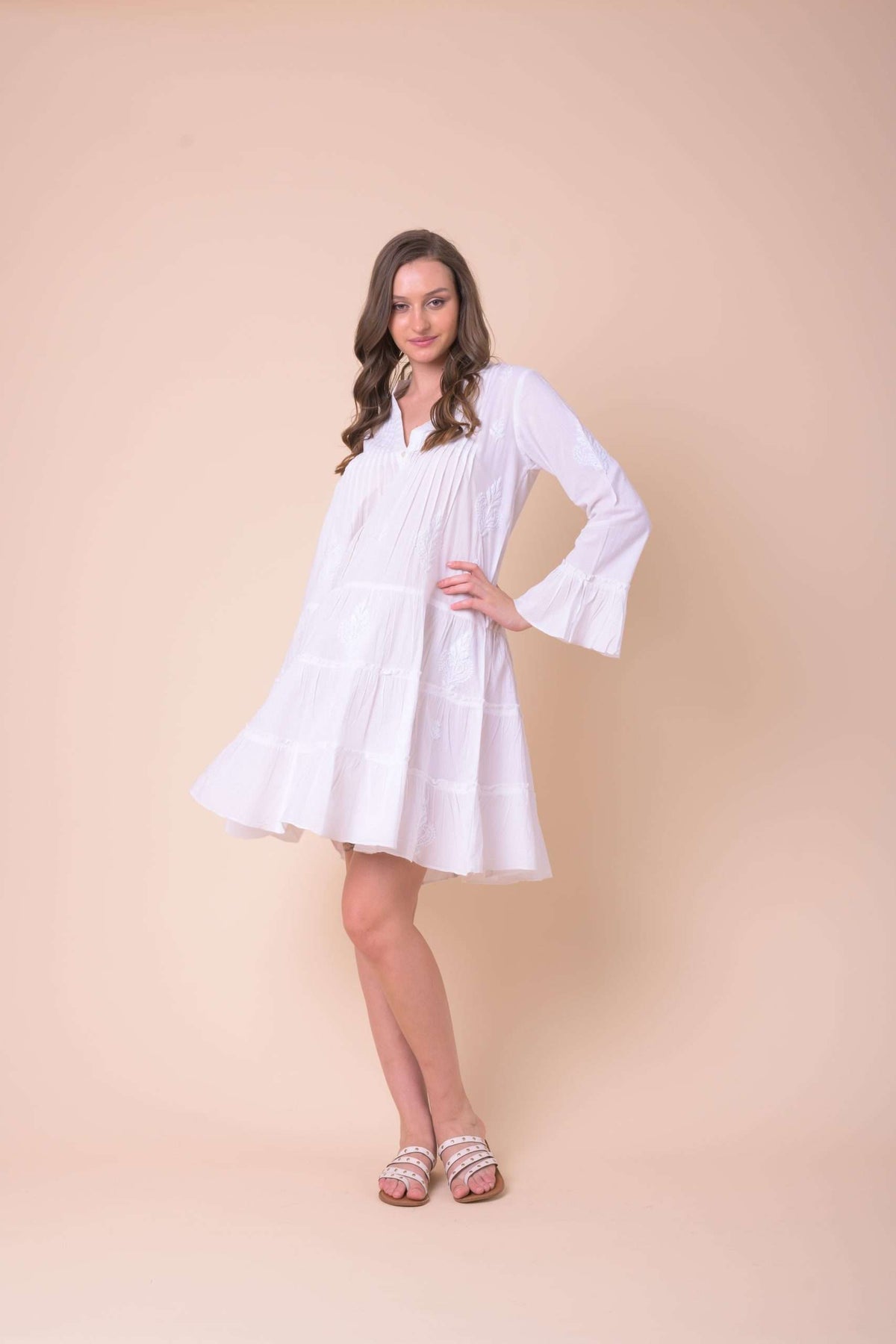 White dress with white embroidery with fluted long sleeves quarter placket and short tiered skirt