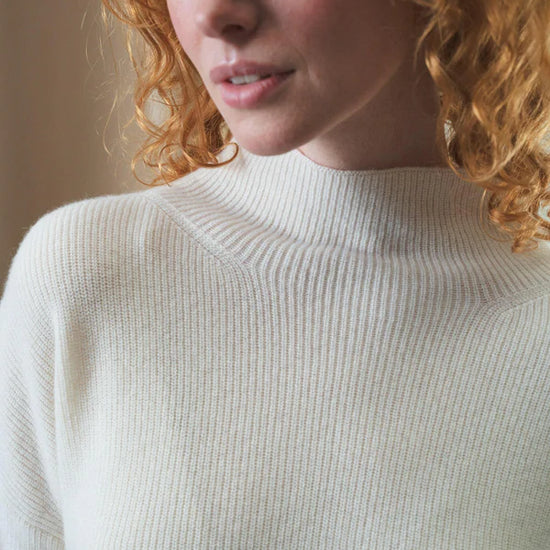 white ribbed jumper with stand neck and long sleeves close up
