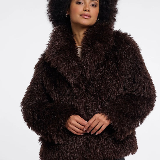 Person wearing a brown fluffy coat on a white background
