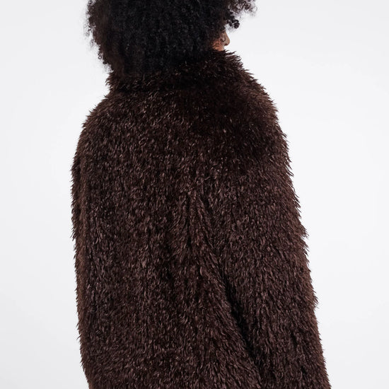 Person wearing a brown fuzzy jacket on a white background