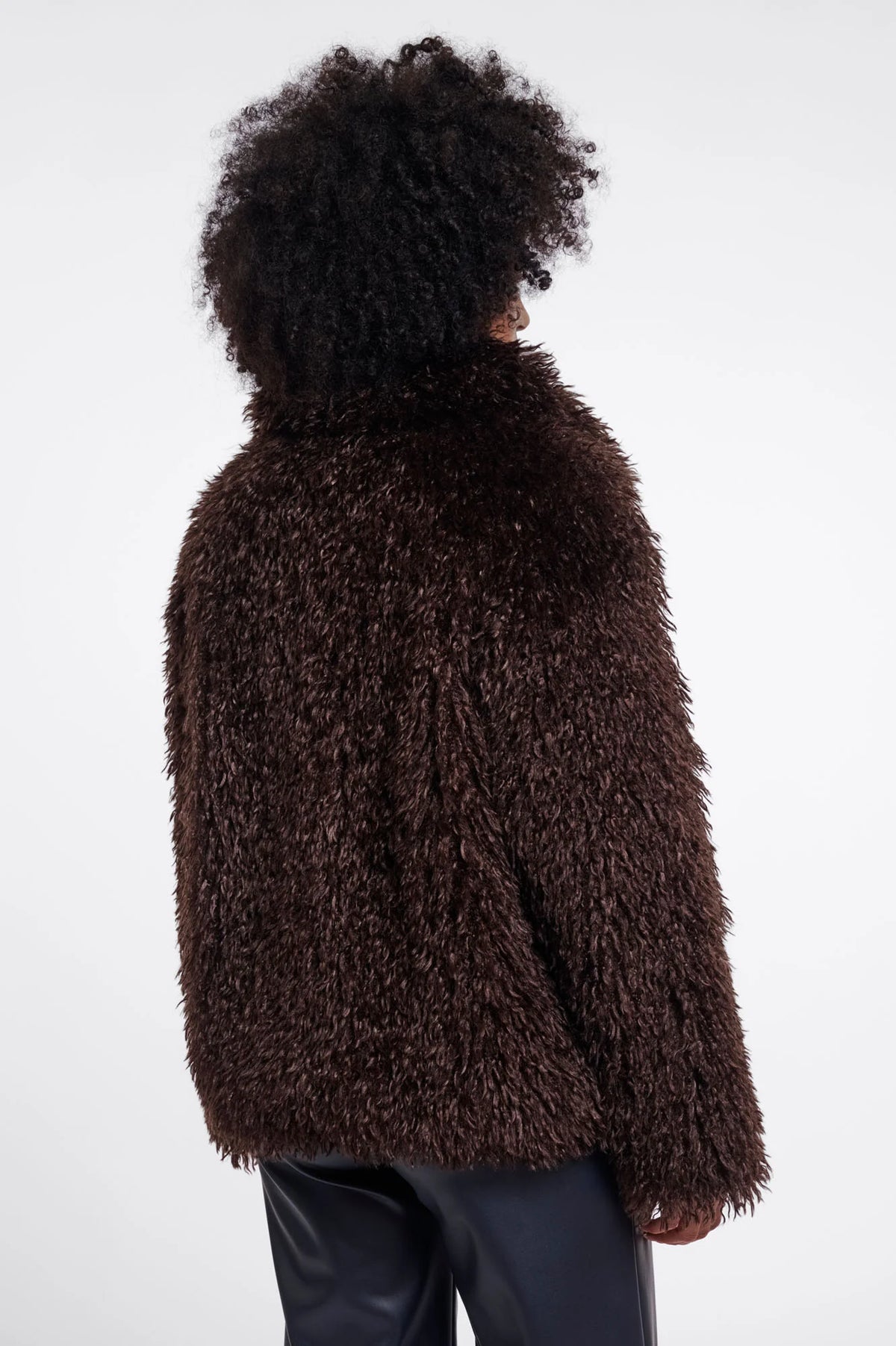 Person wearing a brown fuzzy jacket on a white background