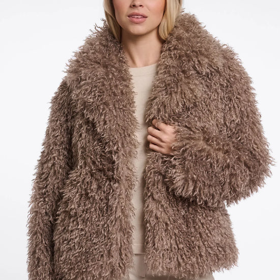 Woman wearing a fluffy brown jacket on a white background