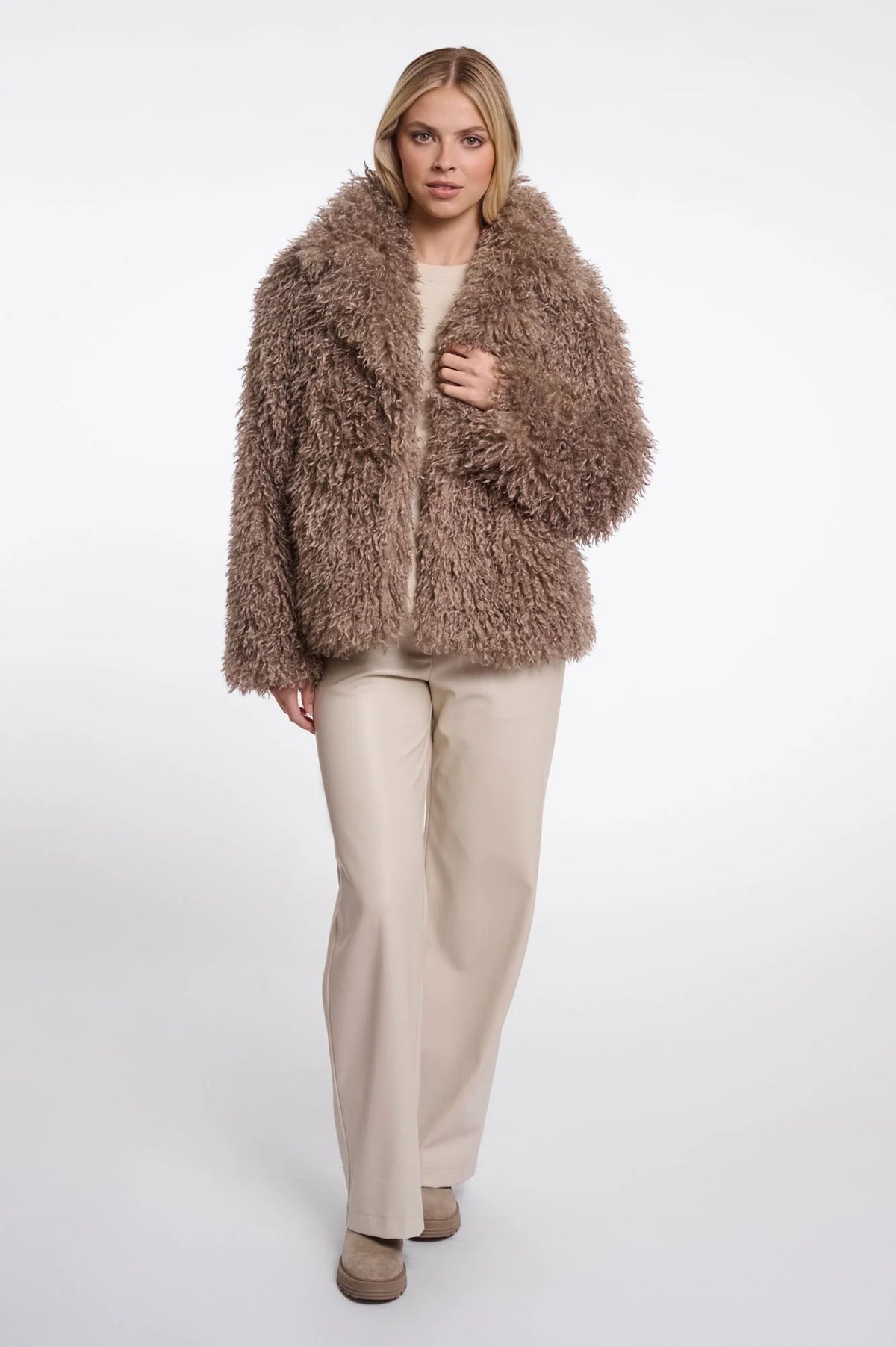 Woman wearing a fluffy brown coat on a white background