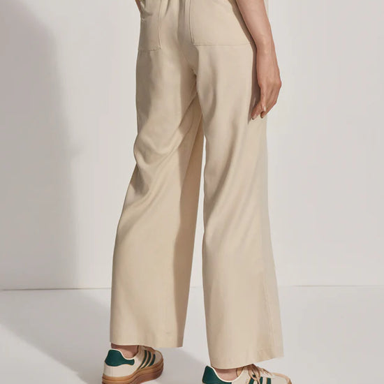 Model wearing loose fitting oyster grey trousers, side view