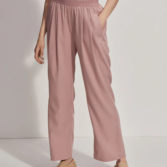 Pink pull on trousers with an elasticated waistband and side pockets model shot