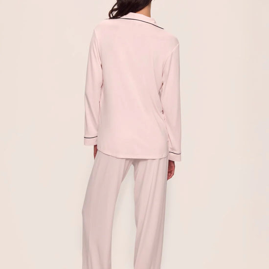Person wearing a light pink pajama set against a plain background