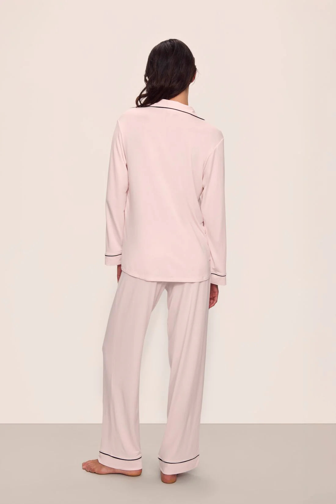 Person wearing a light pink pajama set against a plain background