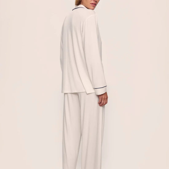 Person wearing a white pajama set against a plain background nfrom Eberjey