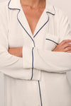 White pajama top with blue piping worn by a person, arms crossed from Eberjey